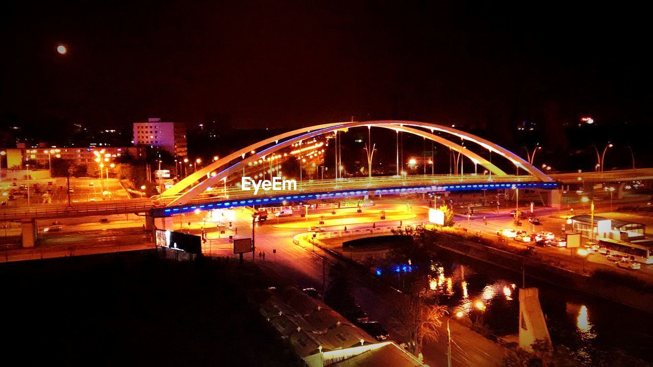 ILLUMINATED BRIDGE OVER RIVER AT NIGHT