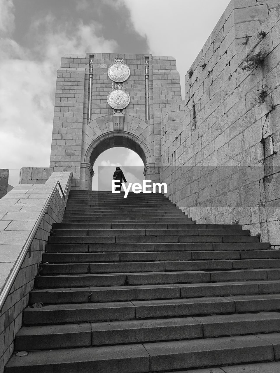 Low angle view of man on staircase by building against sky