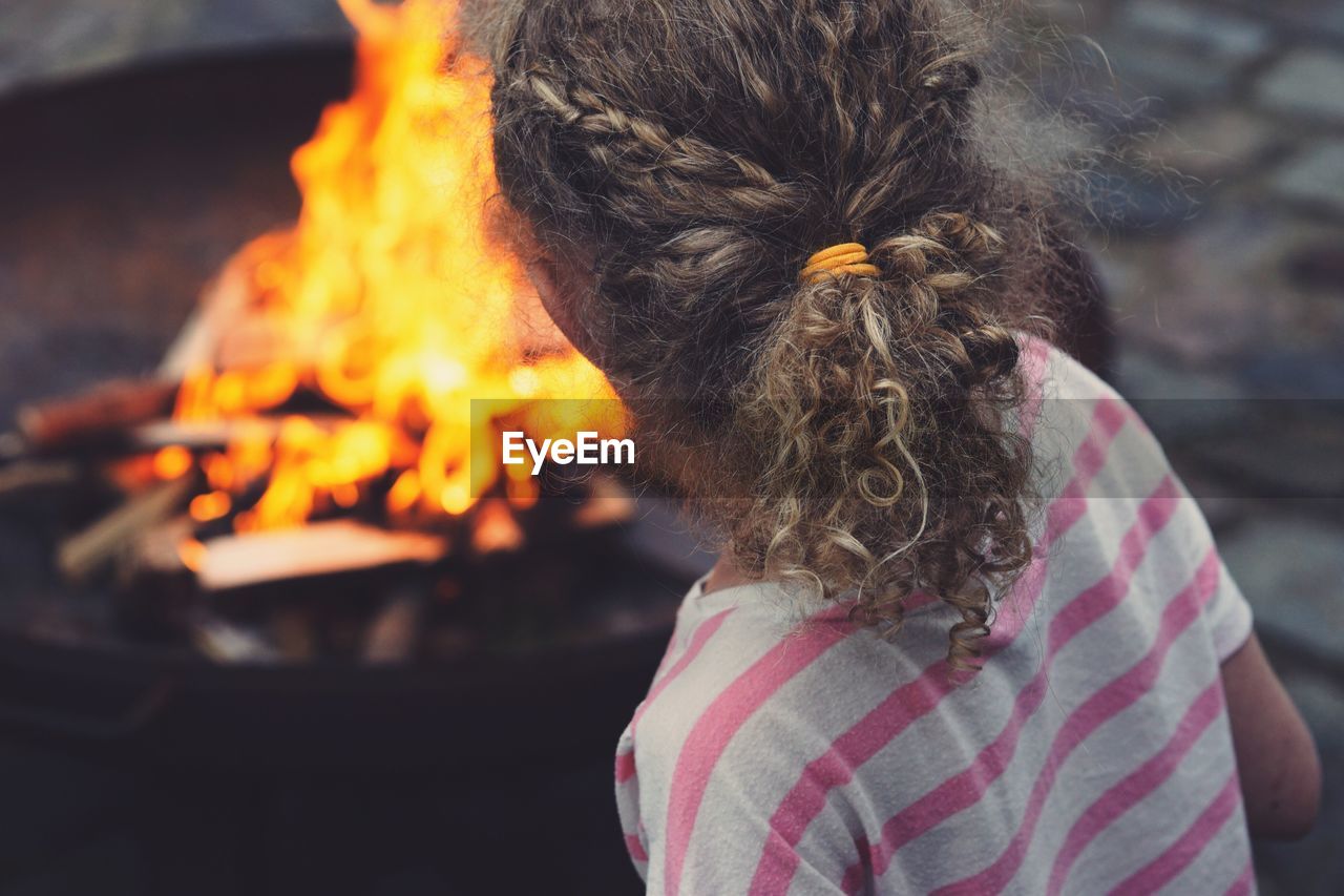 Rear view of girl standing by fire pit at back yard