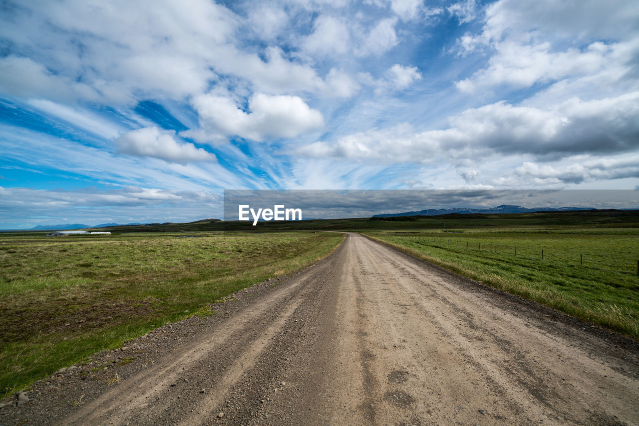 Road amidst field against sky