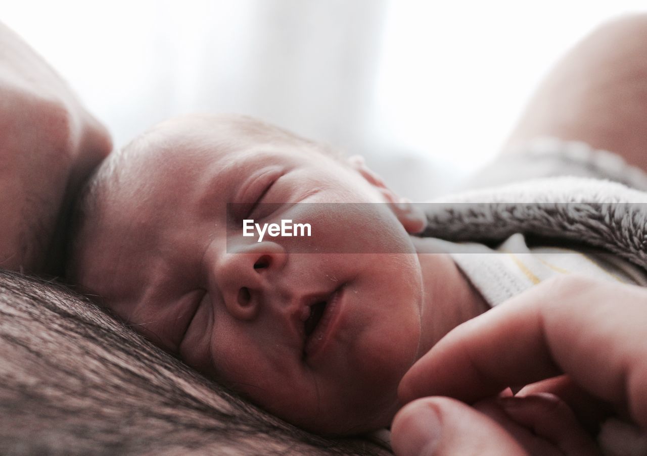 Close-up of baby boy sleeping on father chest