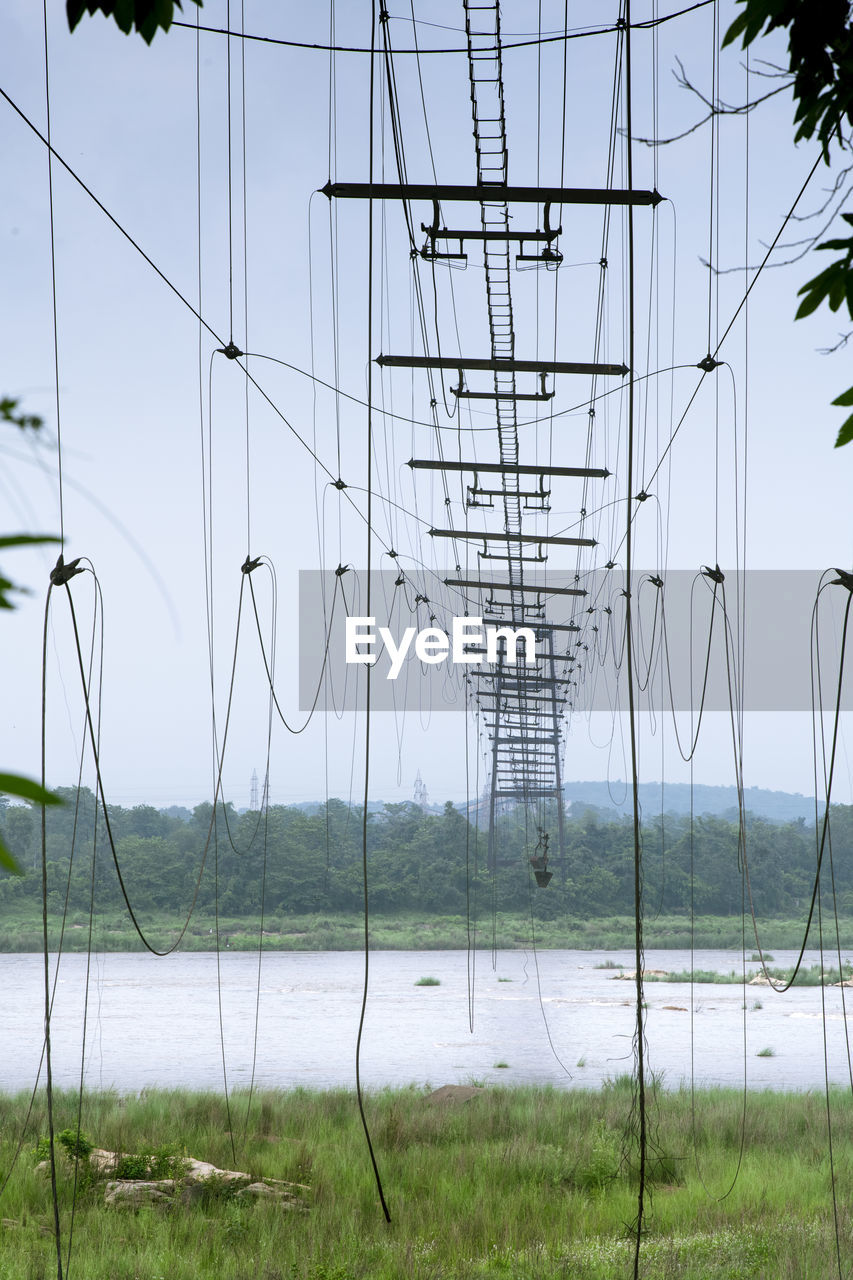 Low angle view of abandoned cable bridge against sky