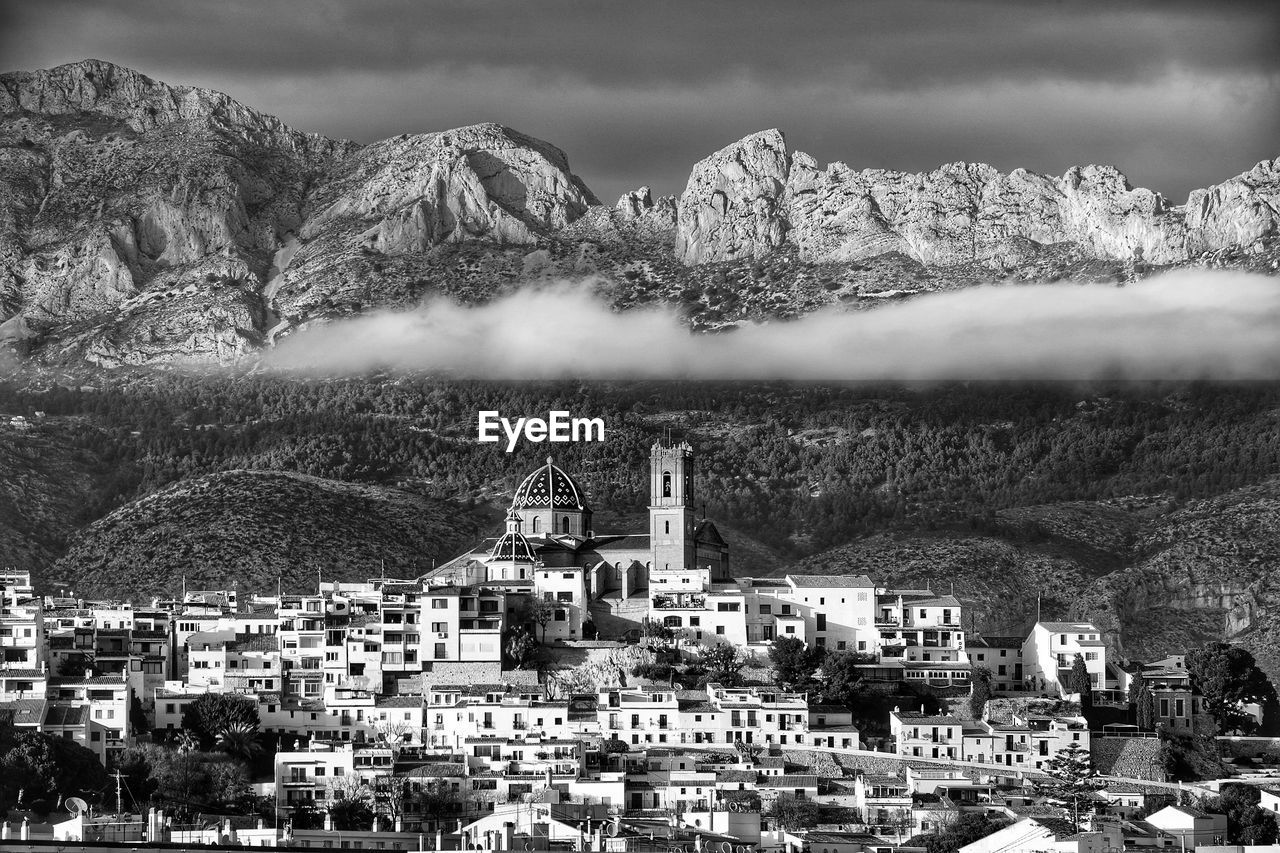 Aerial view of townscape by tree mountain against sky