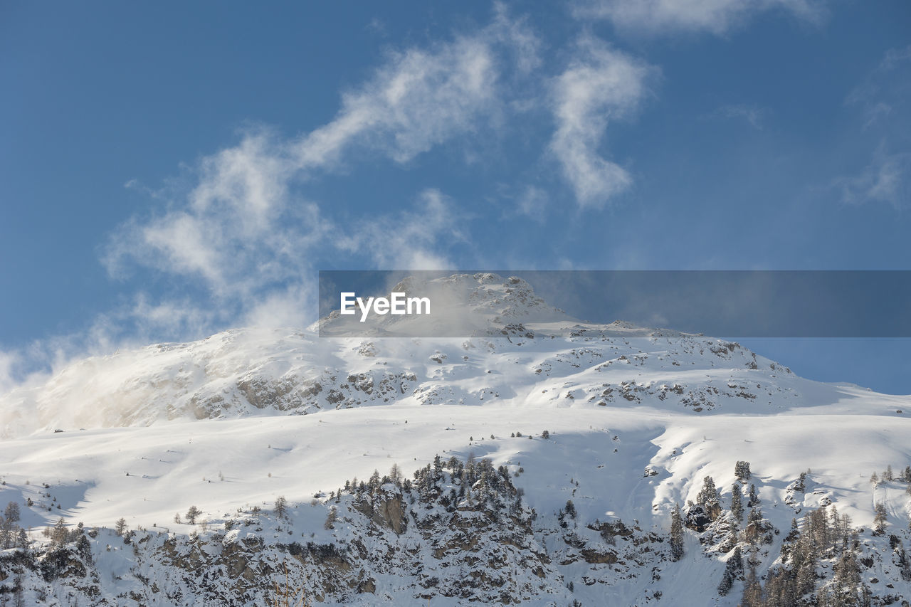 snow, cold temperature, winter, mountain, sky, scenics - nature, environment, beauty in nature, cloud, landscape, mountain range, nature, snowcapped mountain, no people, white, tree, blue, ridge, day, tranquility, tranquil scene, land, forest, travel destinations, non-urban scene, plant, frozen, travel, outdoors, coniferous tree, pine tree, mountain peak, piste, pine woodland, tourism, pinaceae