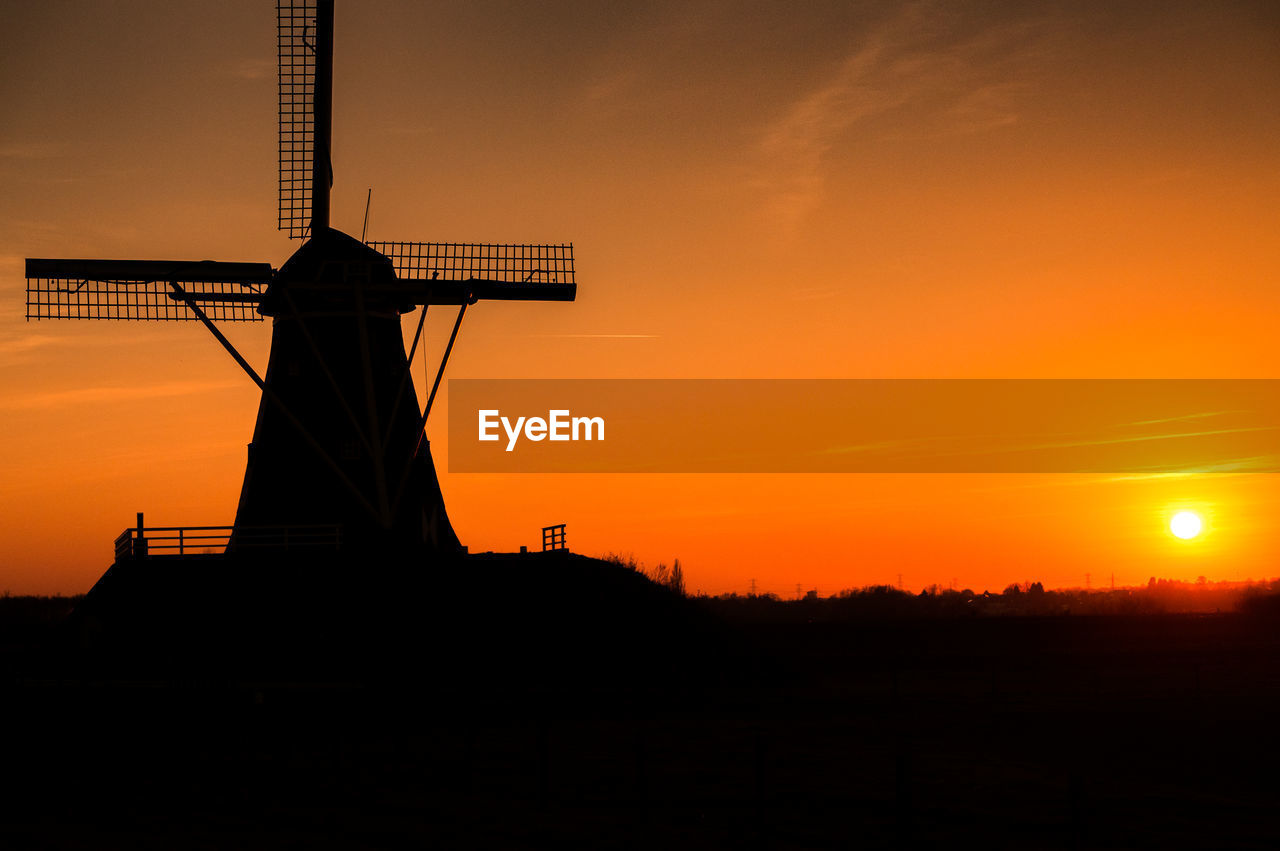 Low angle view of silhouette traditional windmill at sunset