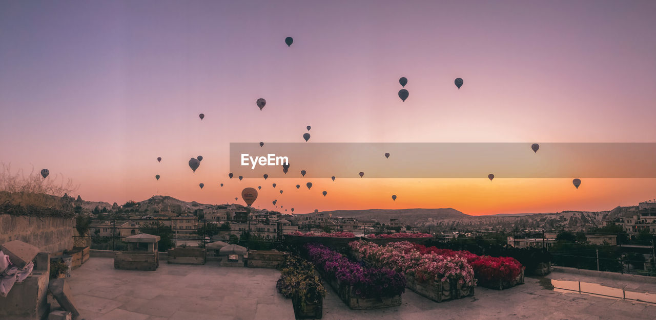 Hot air balloons flying over buildings in city during sunset