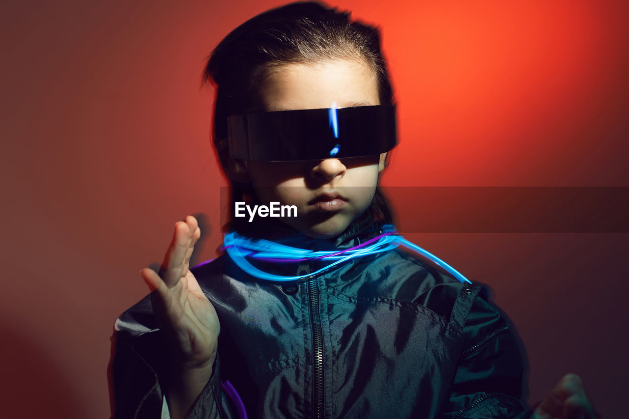 Portrait cyberpunk boy child in vr glasses in blue and red tones with wires. game, virtual reality