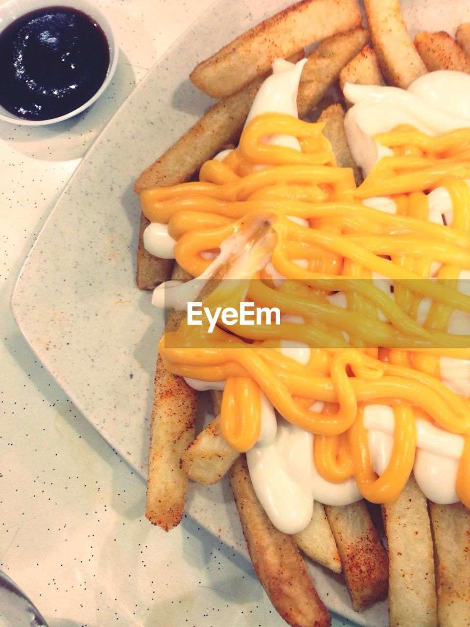 Close-up of fries with mustard and white sauce