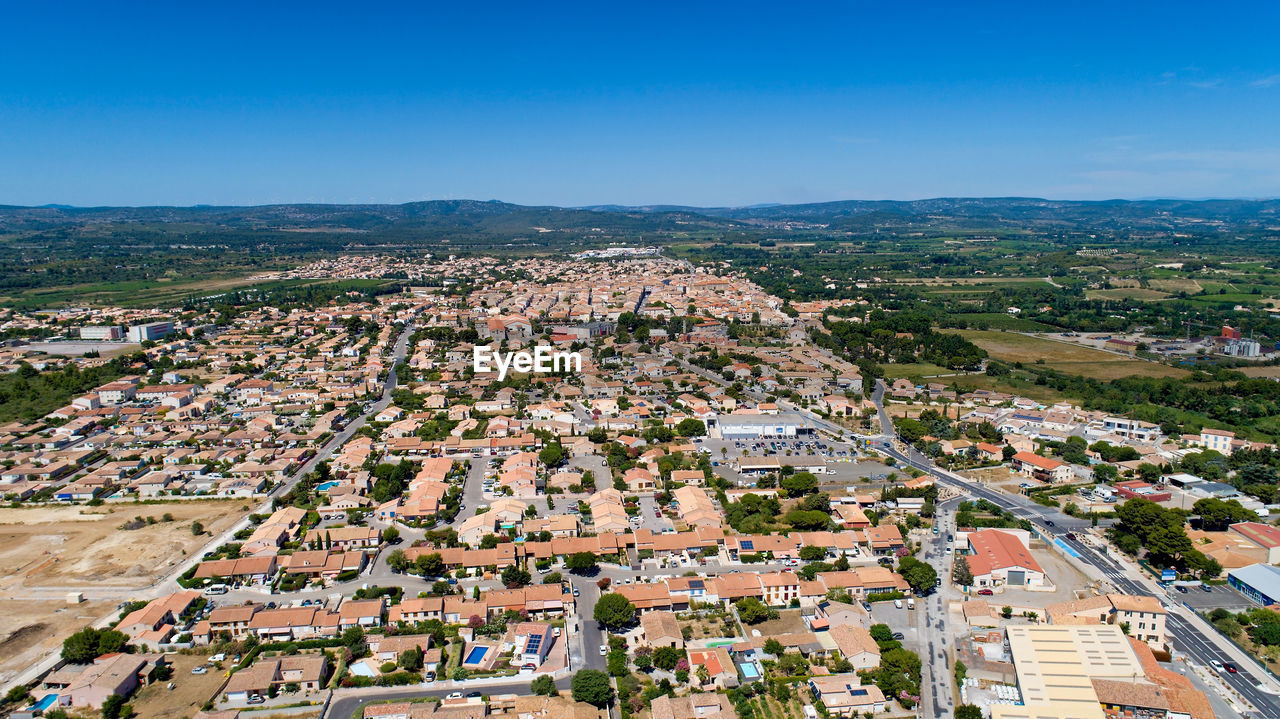 Aerial view of cityscape against blue sky