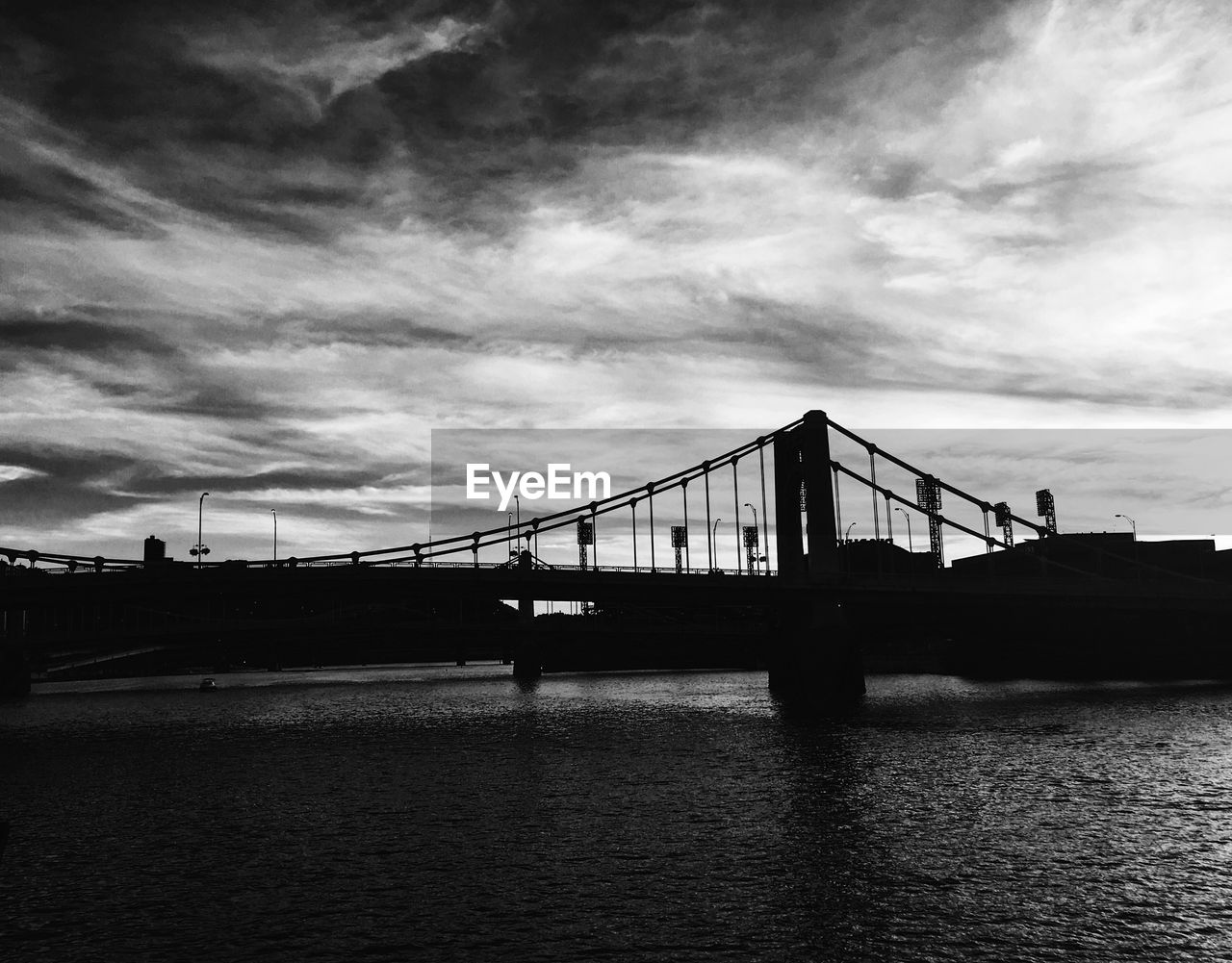 Suspension bridge against cloudy sky