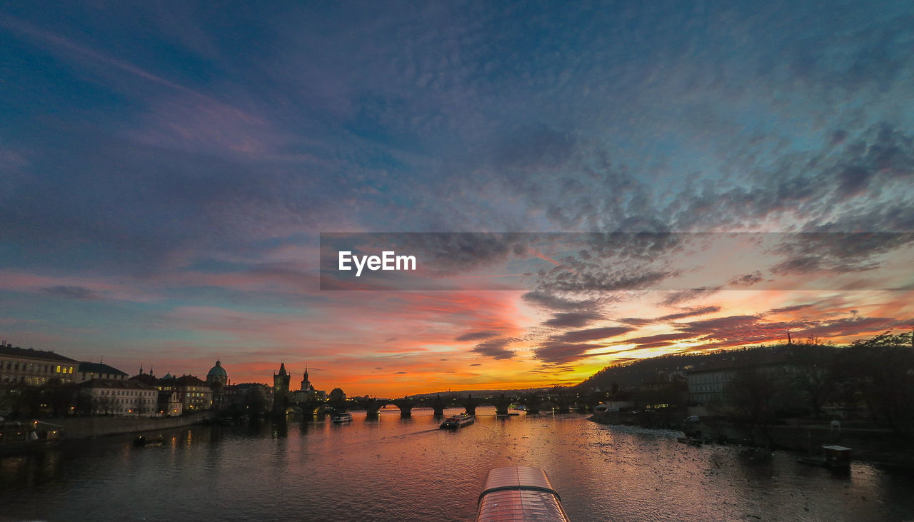 SCENIC VIEW OF RIVER BY CITY AGAINST SKY DURING SUNSET
