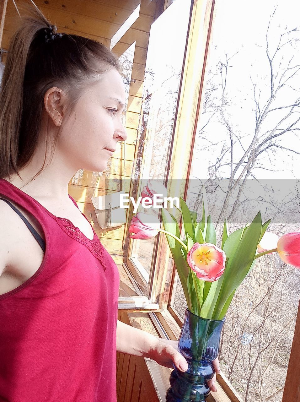 YOUNG WOMAN LOOKING DOWN WHILE HOLDING FLOWER