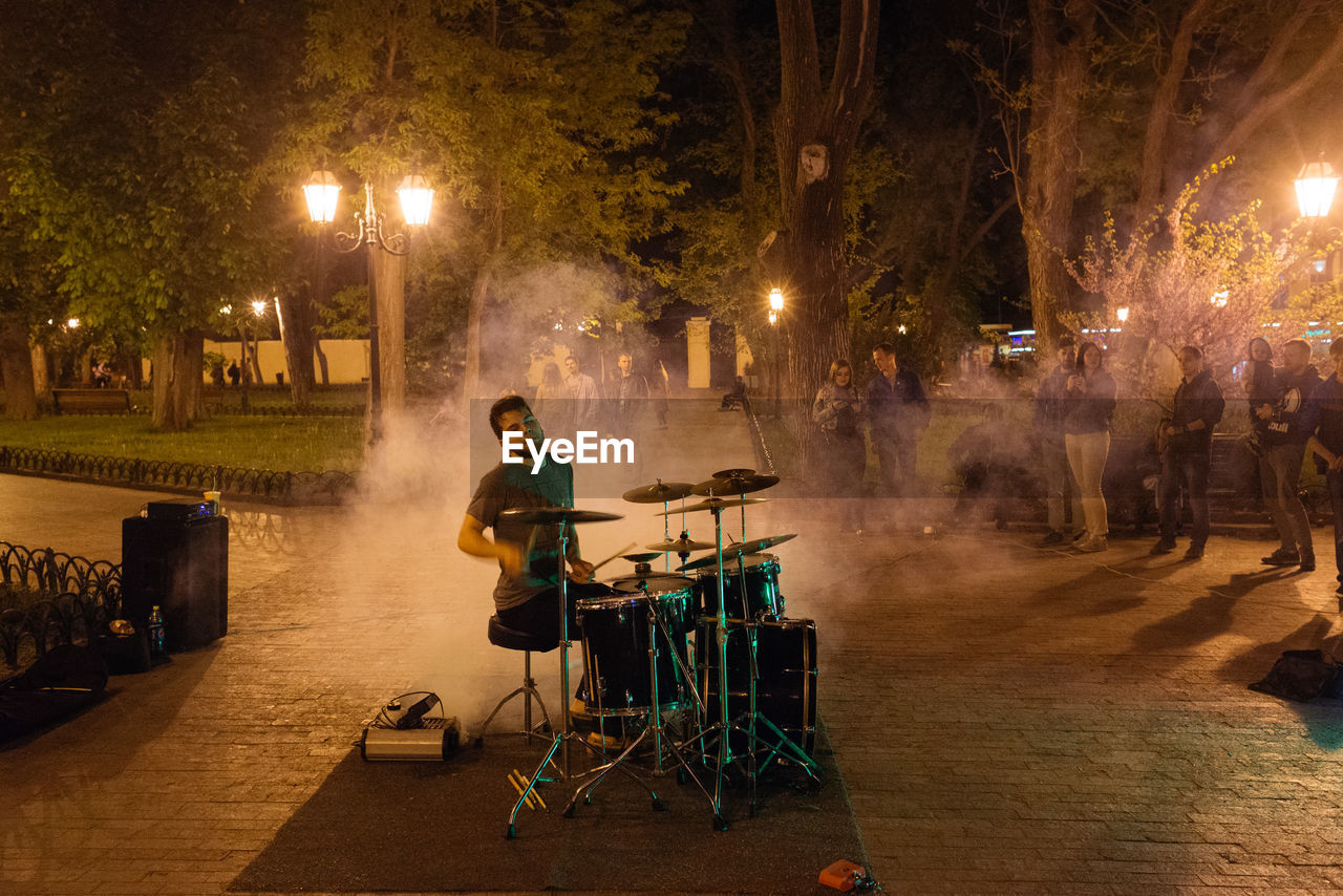 MAN WITH ILLUMINATED LIGHTING EQUIPMENT AT NIGHT