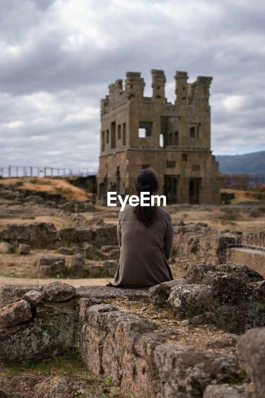 Rear view of woman looking at abandoned built structure