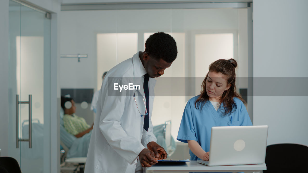 Doctor showing file folder to nurse at desk