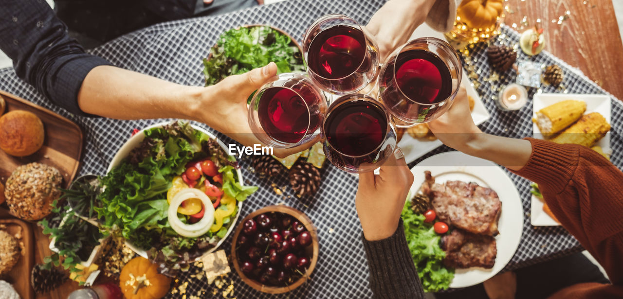 Cropped hands toasting wine at dining table