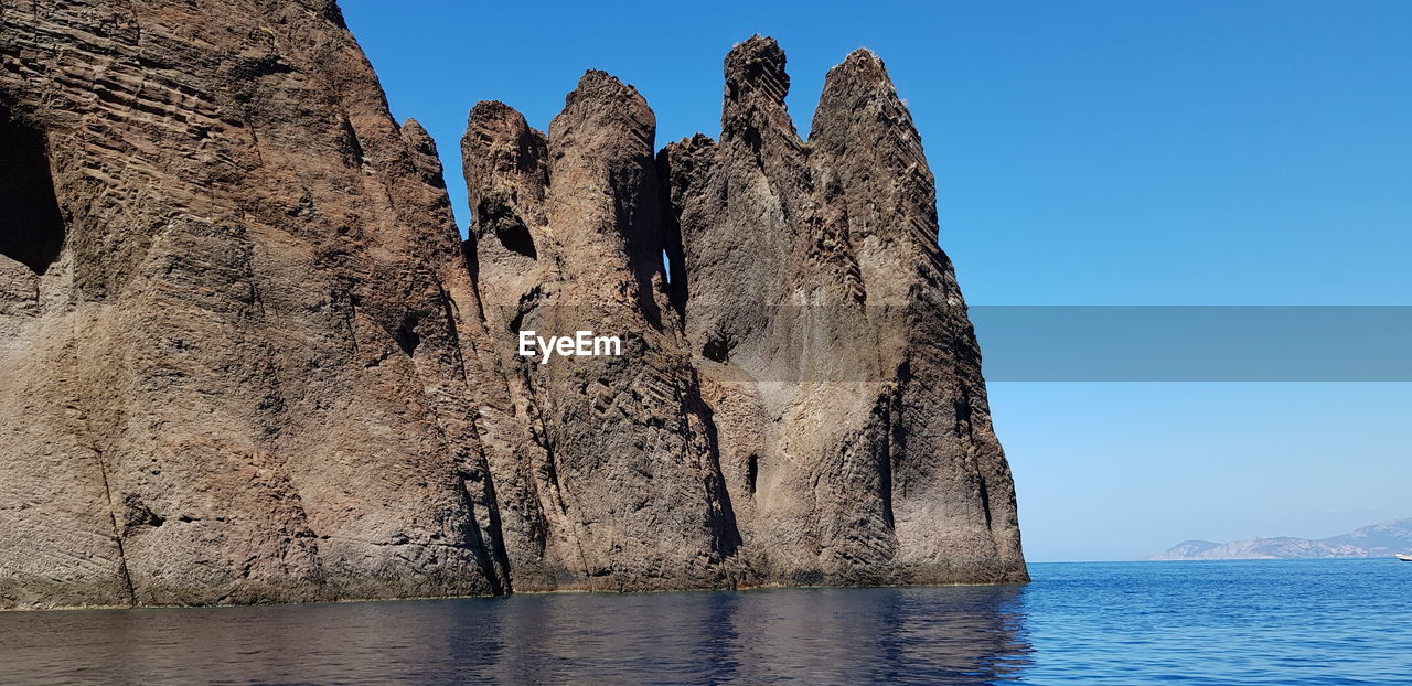 Low angle view of rock formation in sea against clear sky