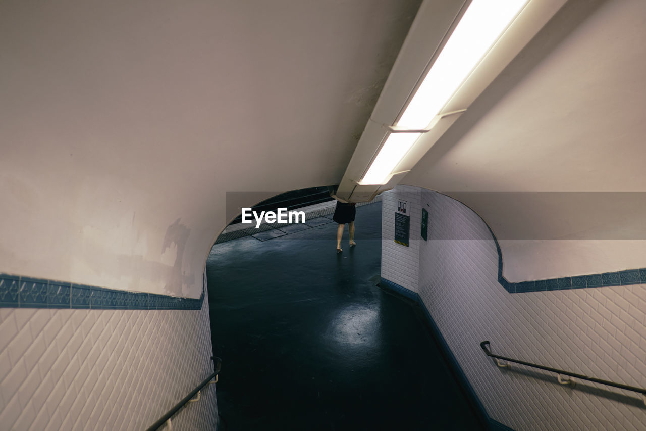 Low section of woman walking in illuminated subway station