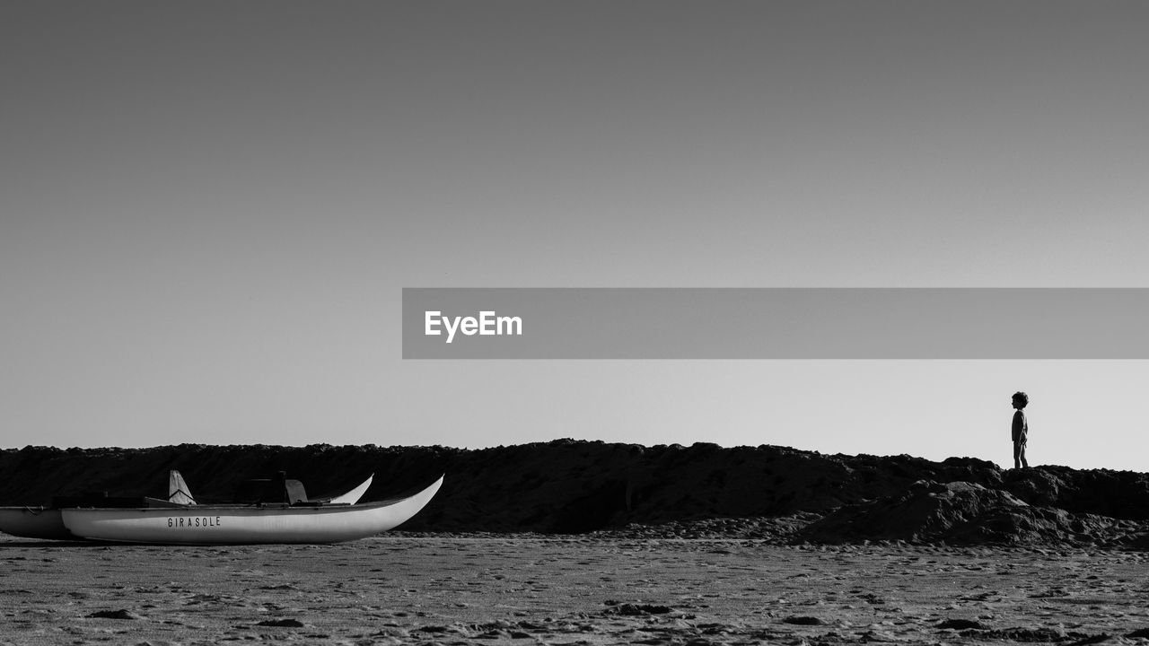 Boats moored at beach against clear sky