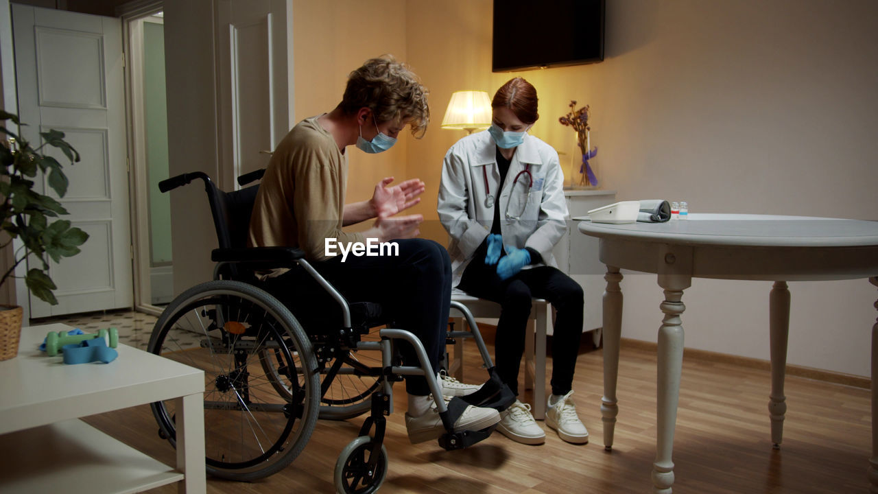 Young nurse checking temperature of patient at home