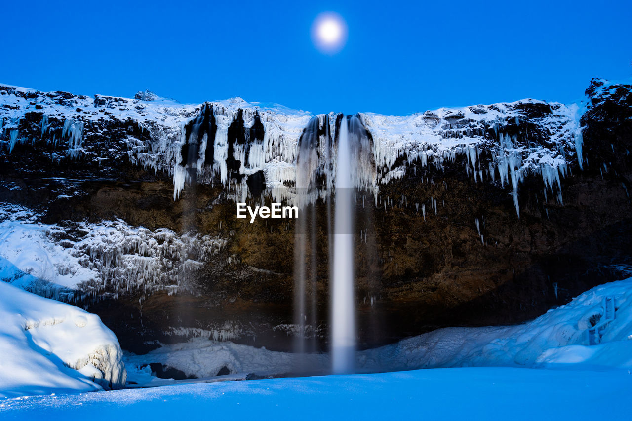 Scenic waterfall under moonlight in winter