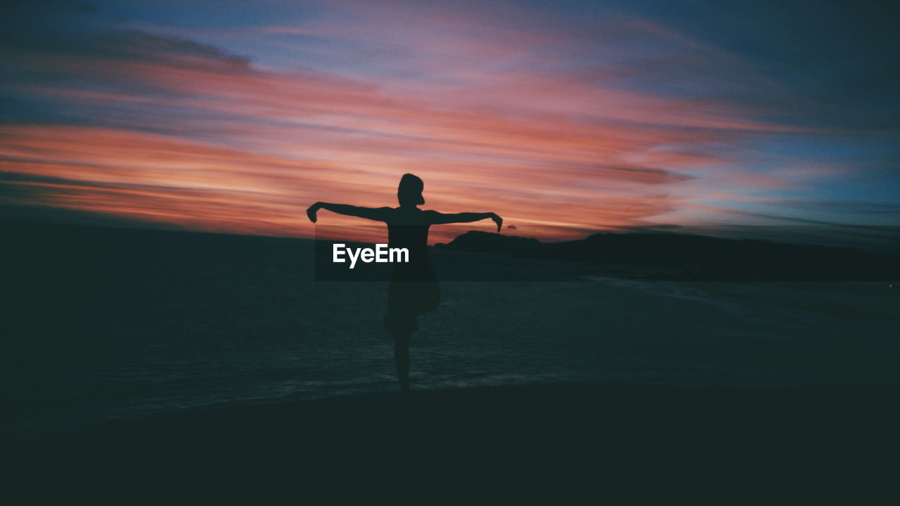 Rear view of man standing on mountain against sky during sunset