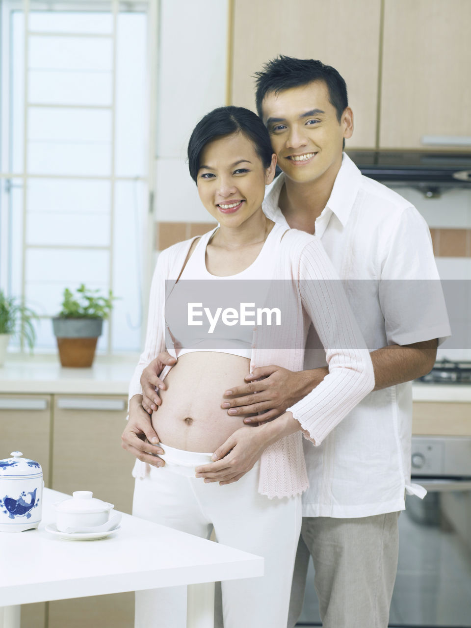Portrait of smiling pregnant woman with man standing at home