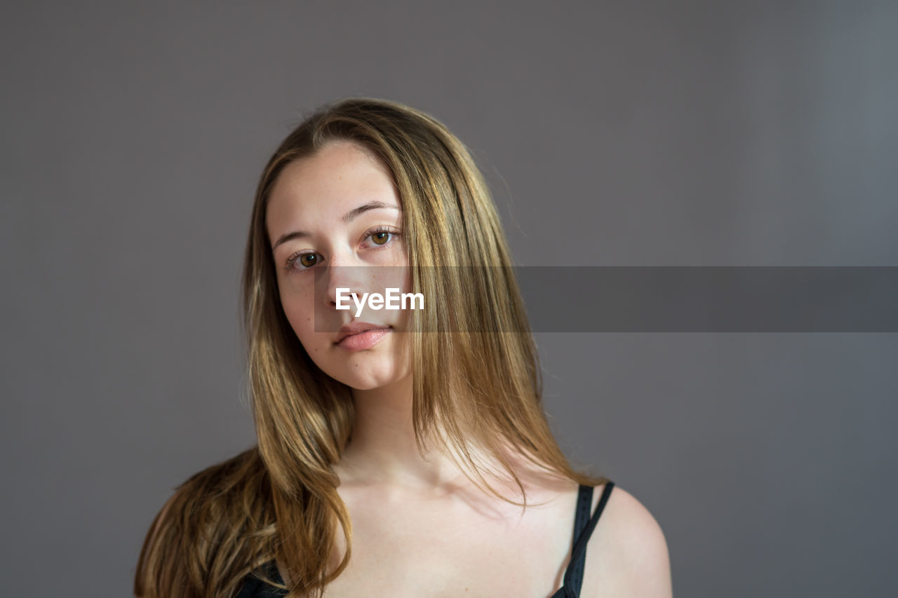 Portrait of a beautiful young woman against gray background