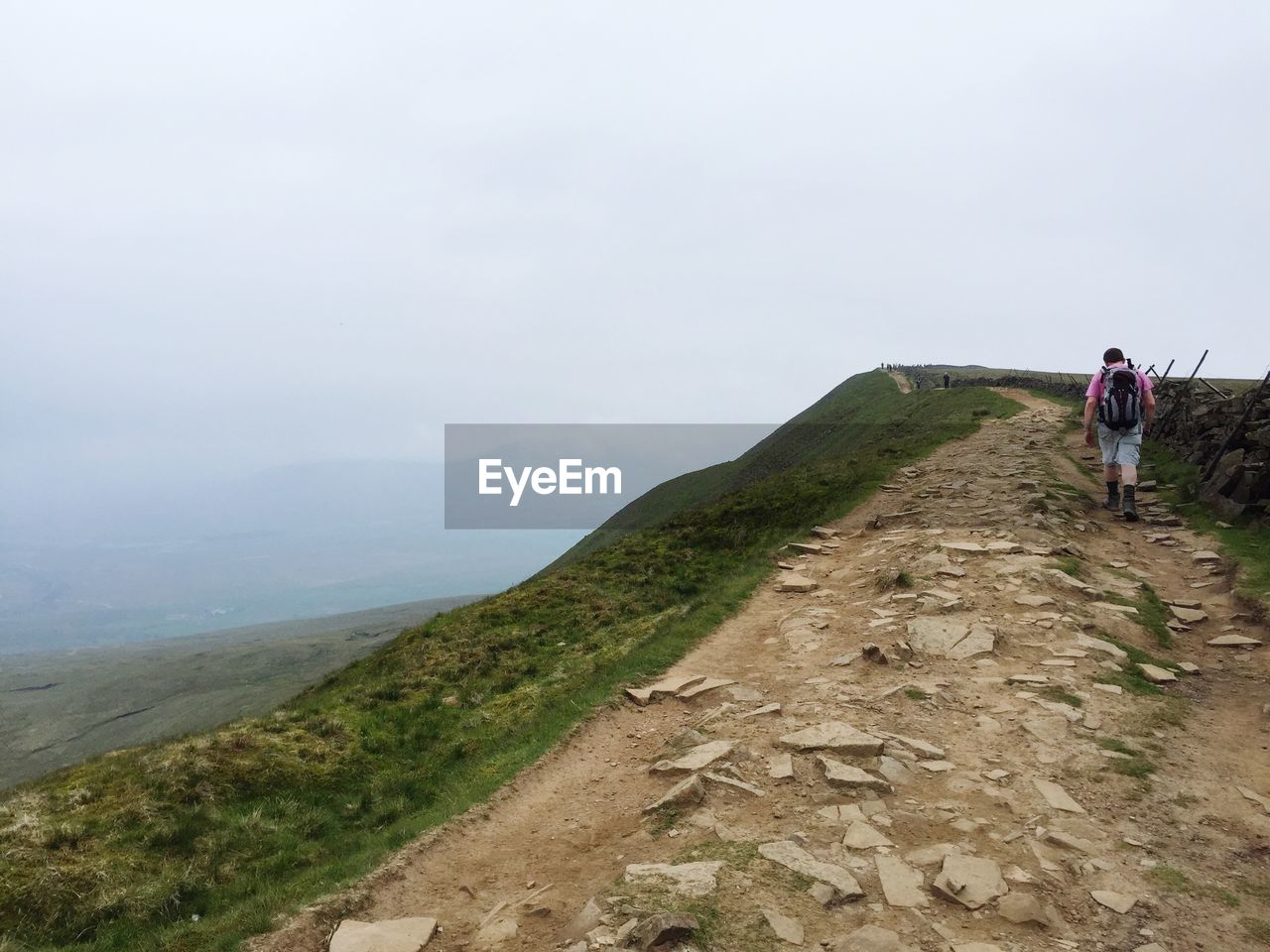 REAR VIEW OF WOMAN STANDING ON MOUNTAIN LANDSCAPE