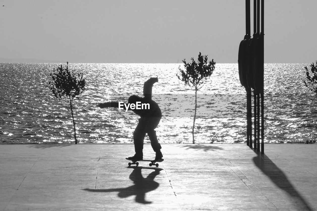 Silhouette person skateboarding at seaside