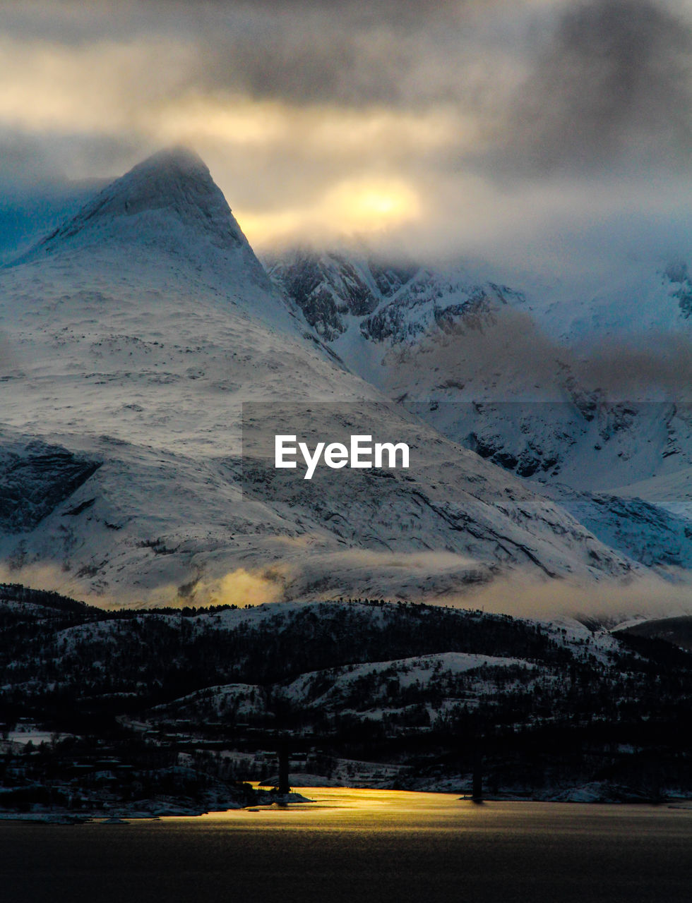 Scenic view of snow covered mountains against cloudy sky