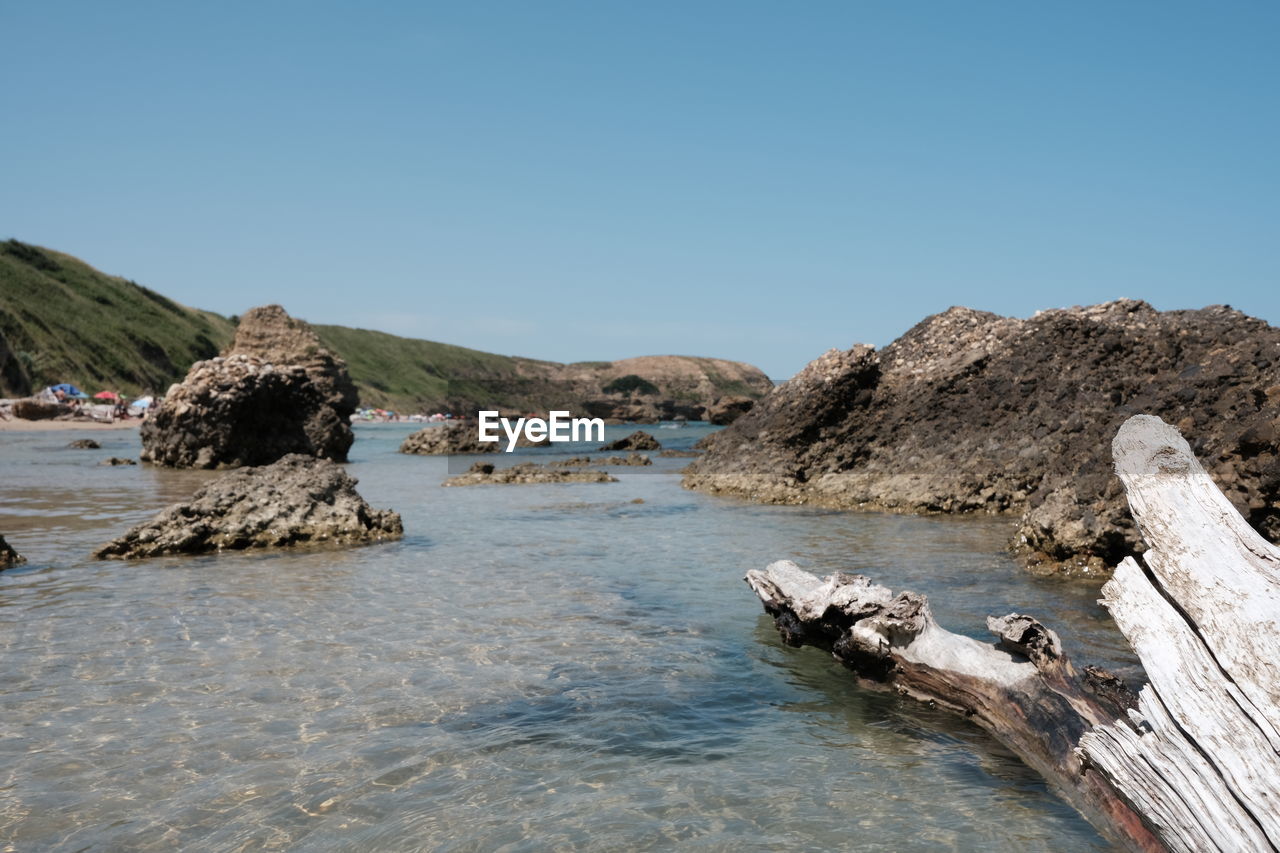 Scenic view of rocks in sea against clear sky