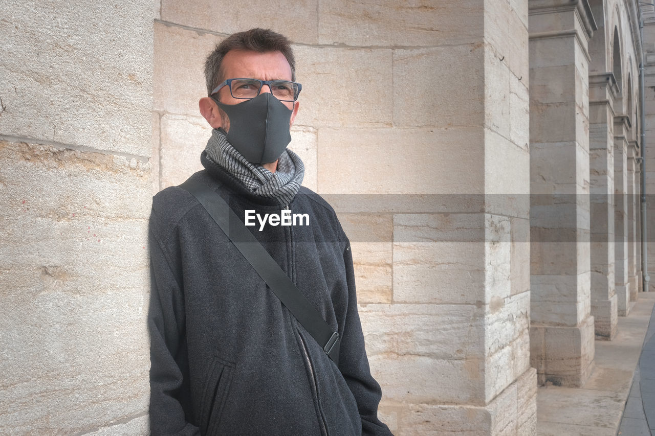 Man wearing sunglasses standing against wall