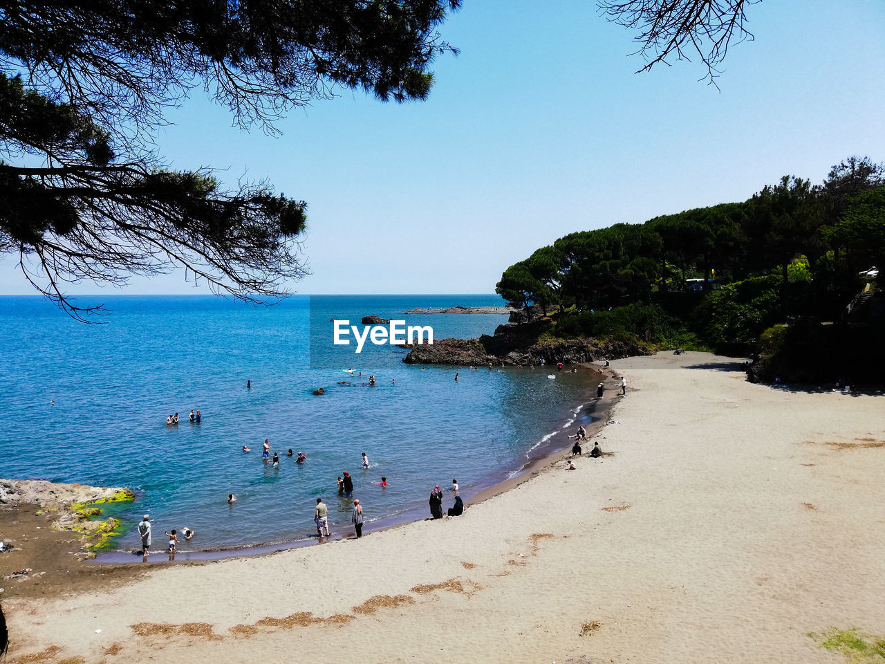 PEOPLE AT BEACH AGAINST CLEAR SKY