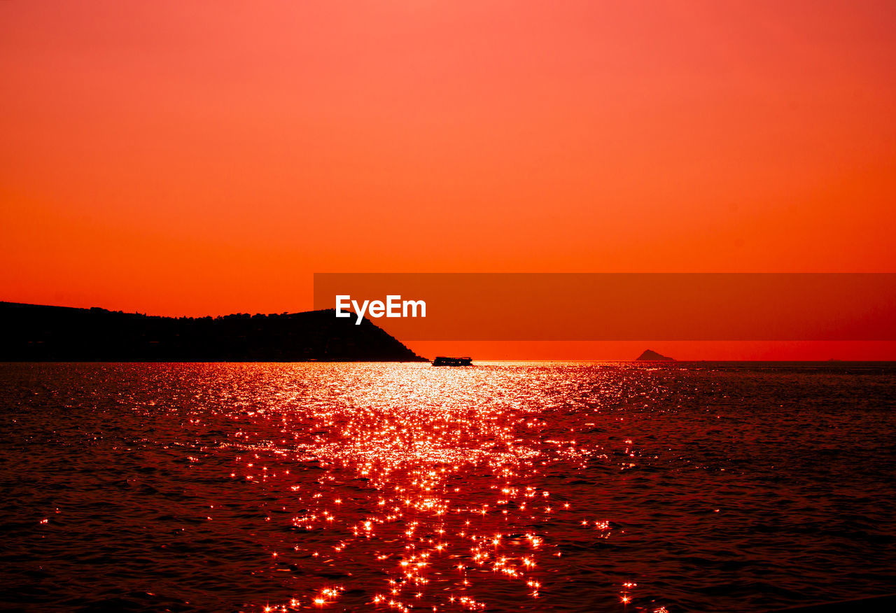 Scenic view of sea against orange sky