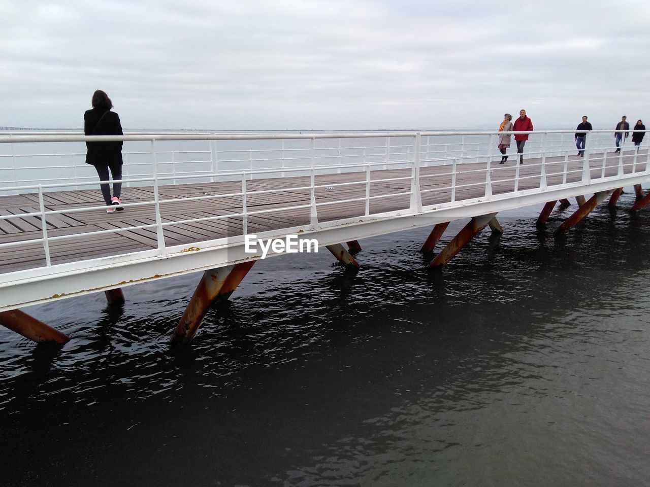 People on pier over sea