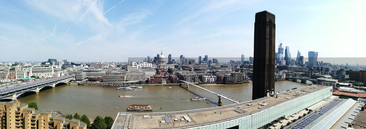 High angle view of city buildings by river against sky