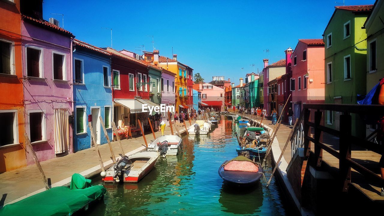 BOATS MOORED ON CANAL AMIDST BUILDINGS IN CITY