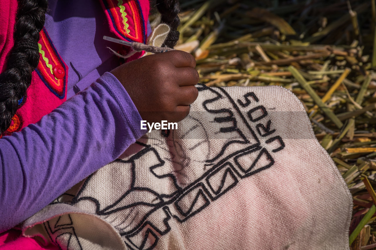 Midsection of woman making embroidery on textile