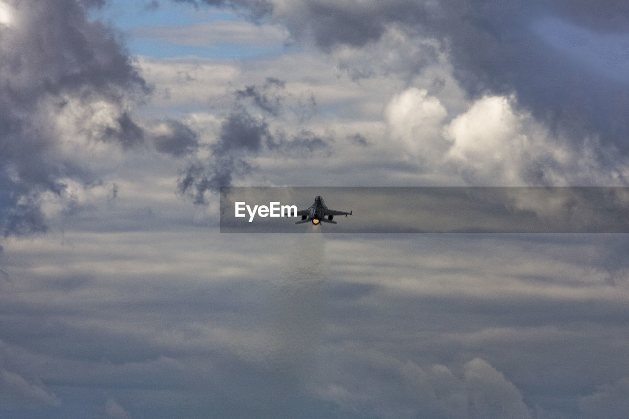 Low angle view of fighter airplane flying in cloudy sky