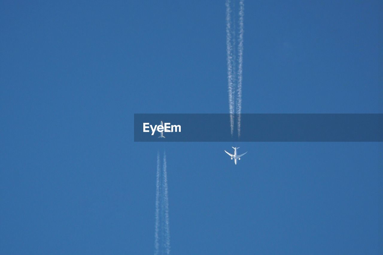 Low angle view of airplane flying against clear blue sky