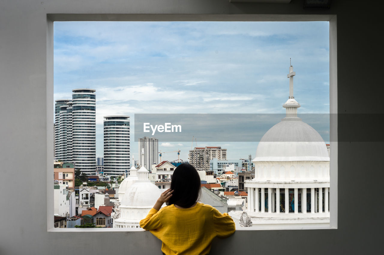 Rear view of woman looking at buildings against sky