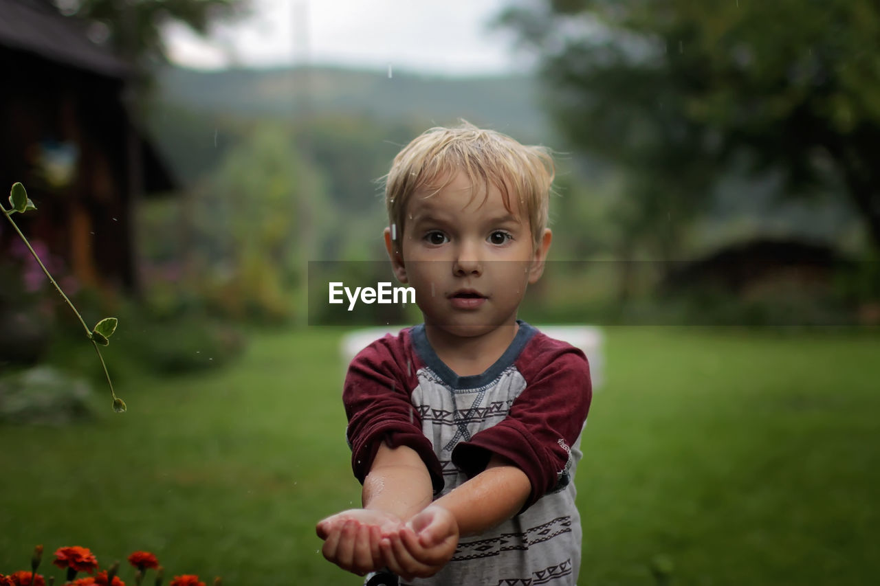 Cute little boy gathering a rain water into his hands, water economy concept