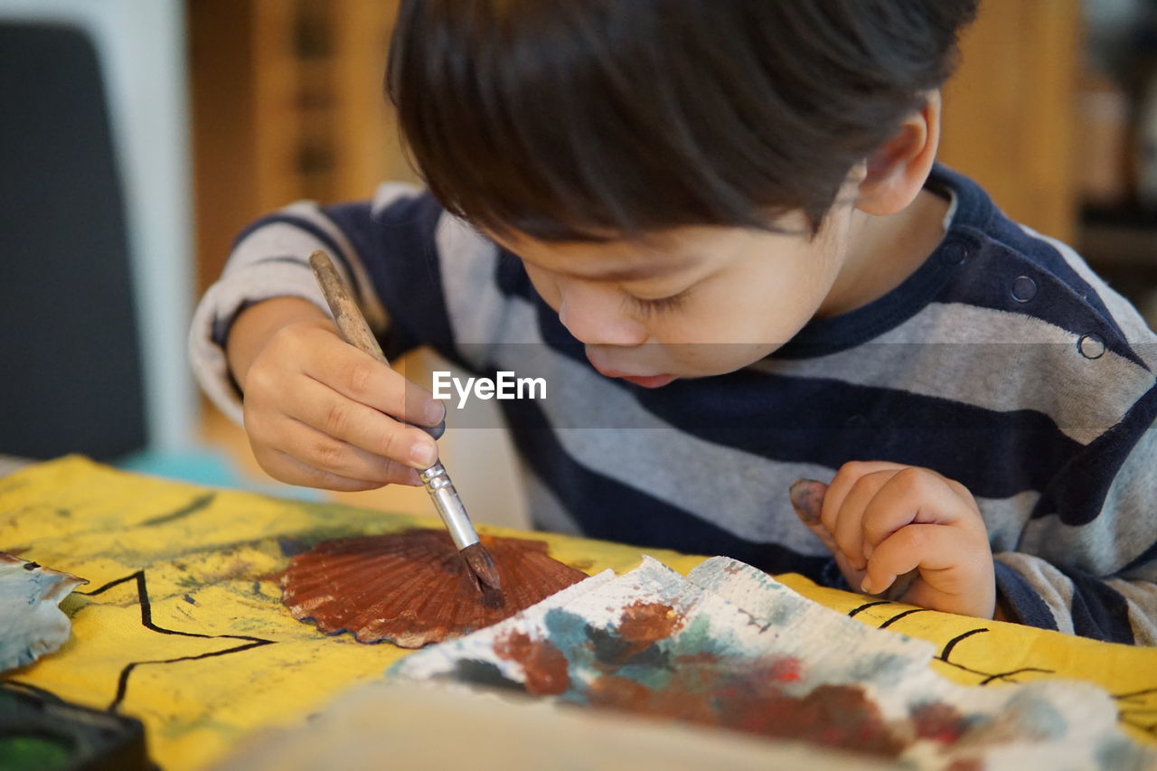 Close-up of boy painting at table