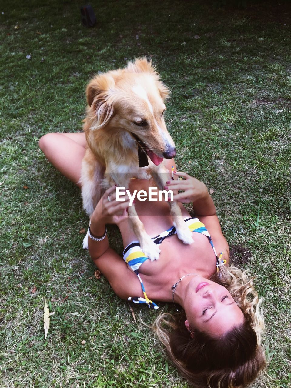 Woman with dog lying on grass 