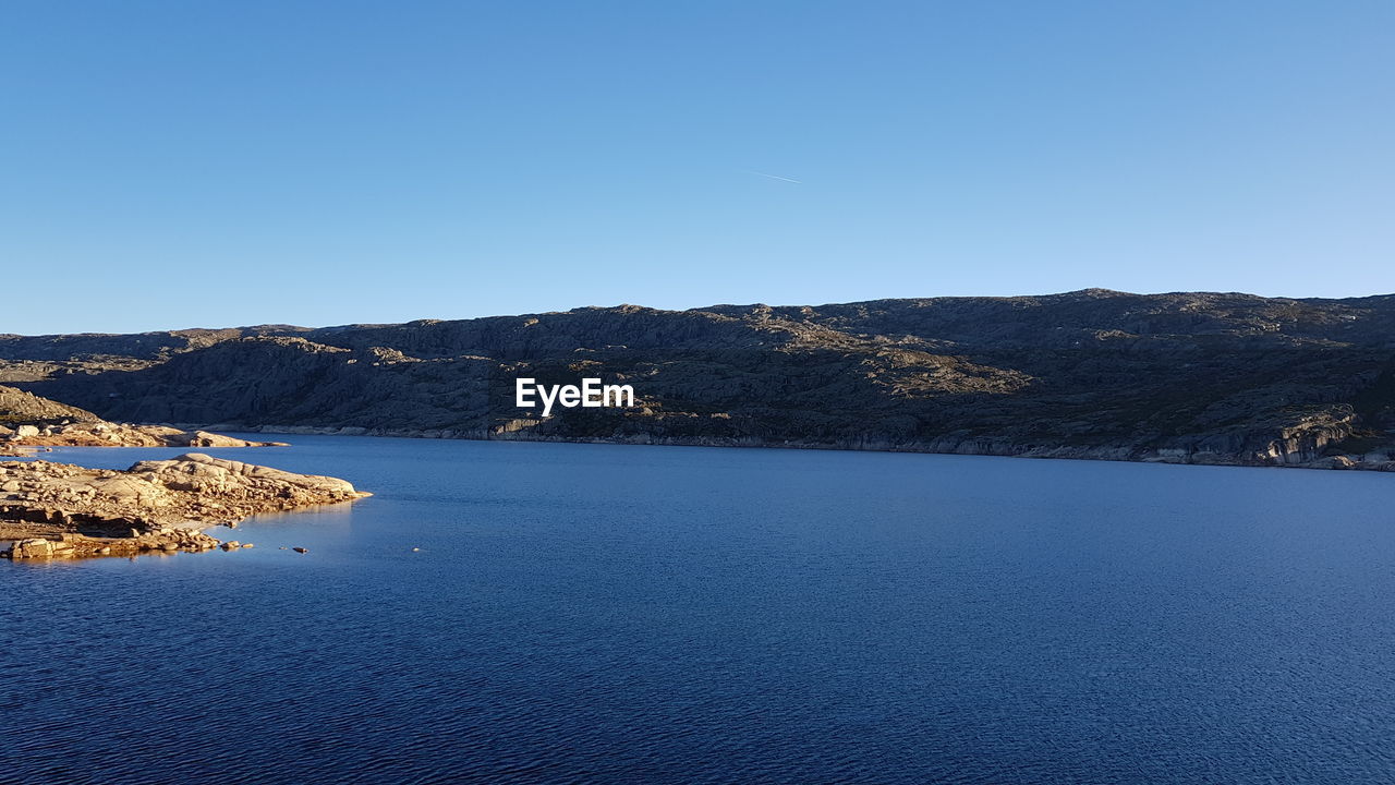 Scenic view of lake against clear blue sky