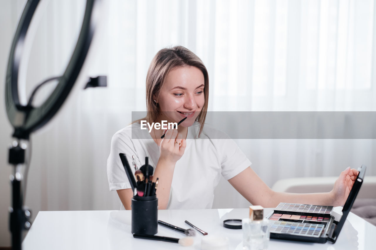 Woman beauty blogger recording vlog video at home about make-up and cosmetics. online influencer