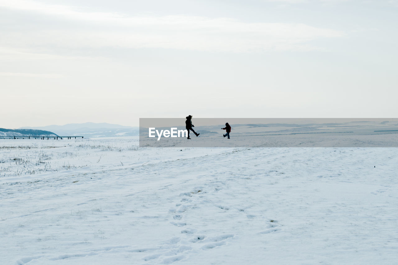 People on snow covered land against sky