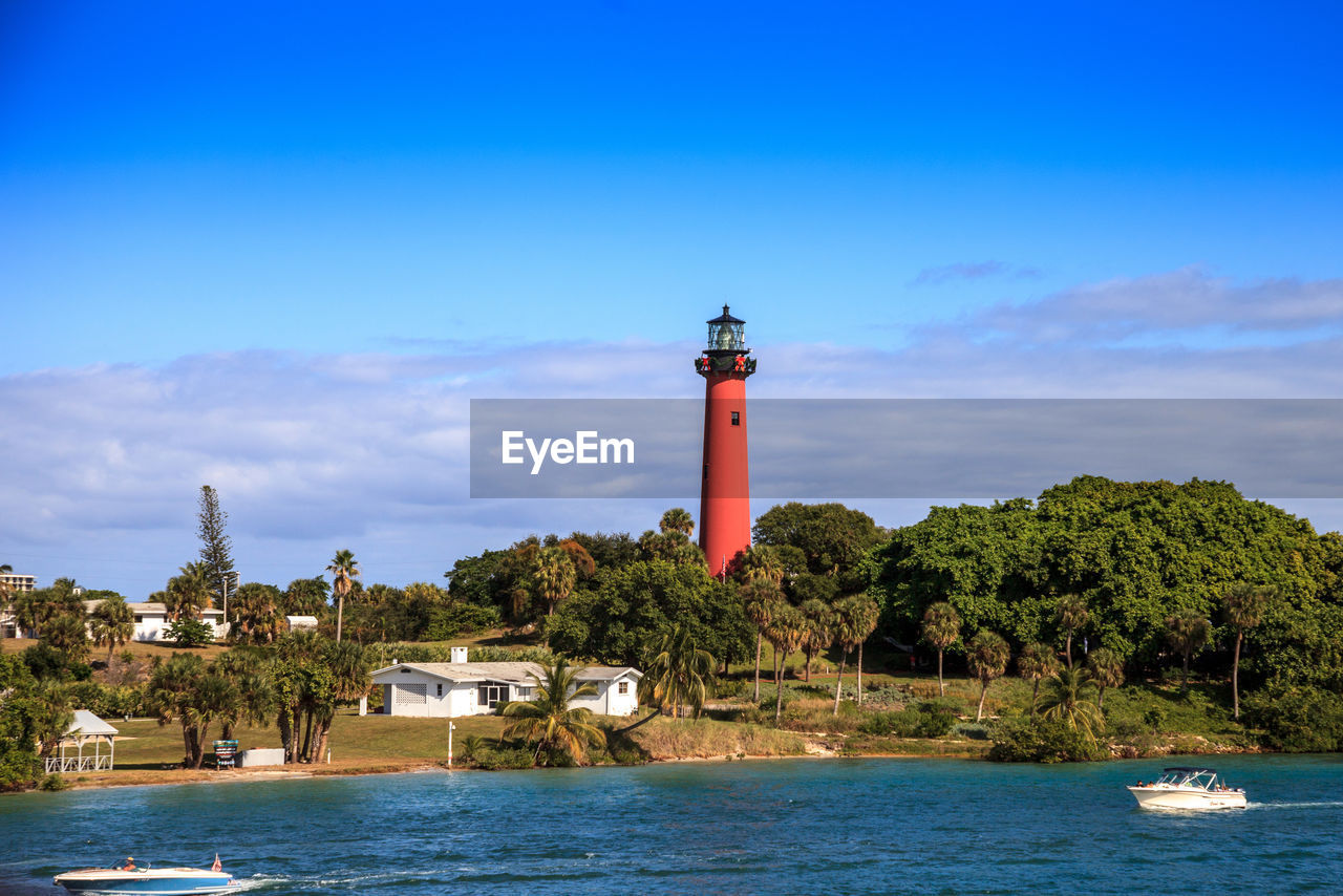 LIGHTHOUSE BY SEA AGAINST BUILDINGS