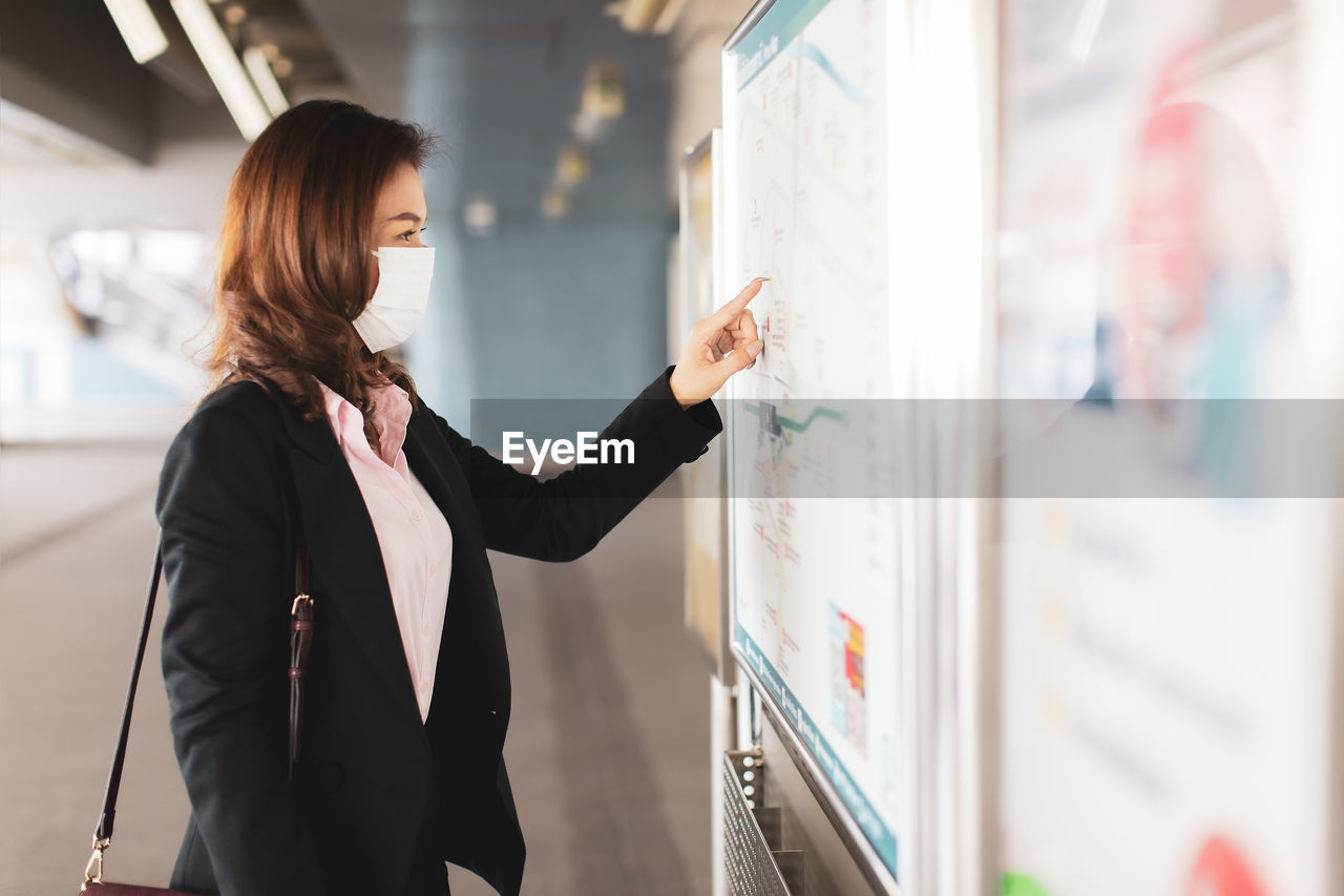 Side view of businesswoman looking at map at subway station